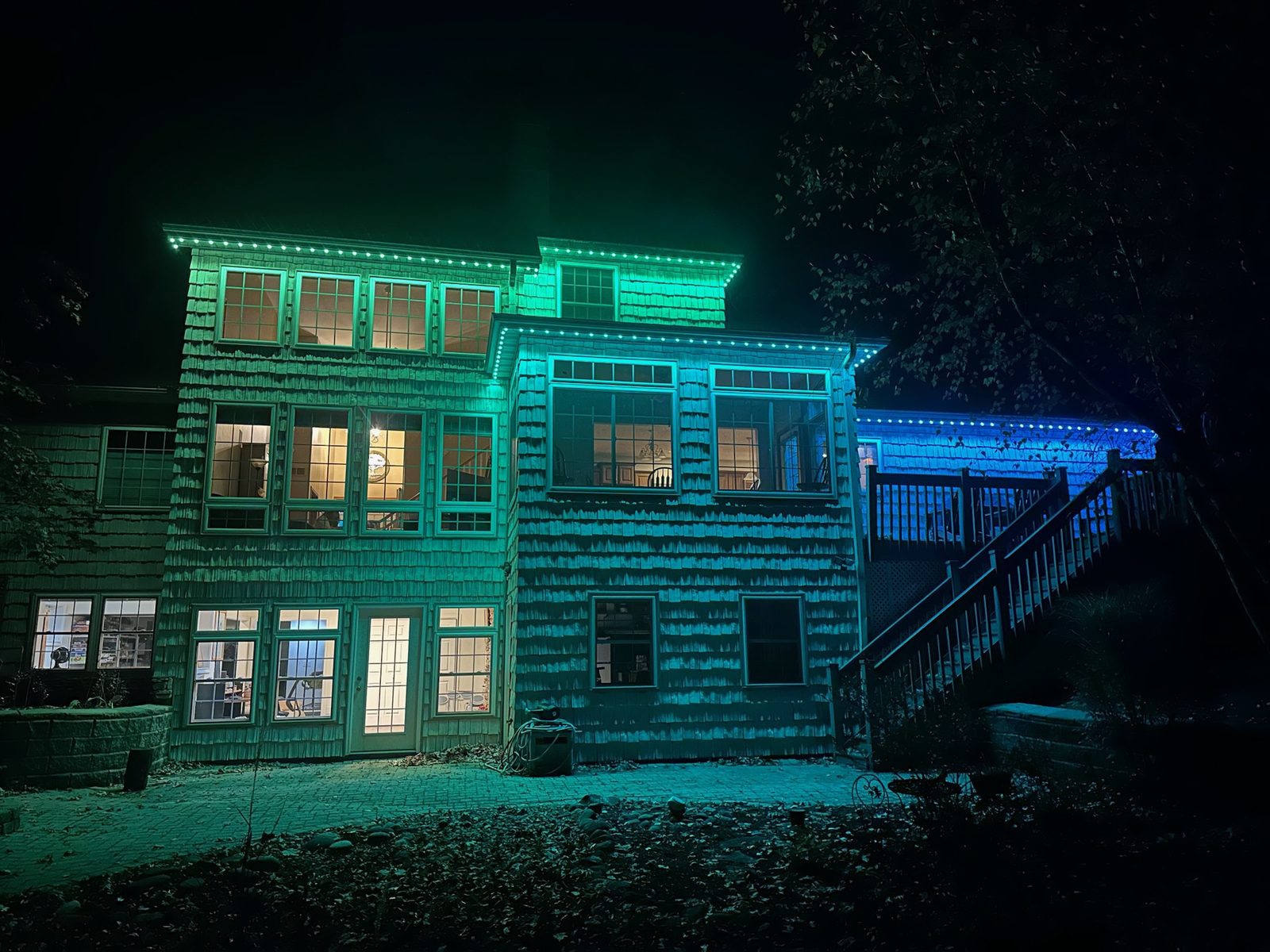 Teal and blue color-changing lighting on a three-story home