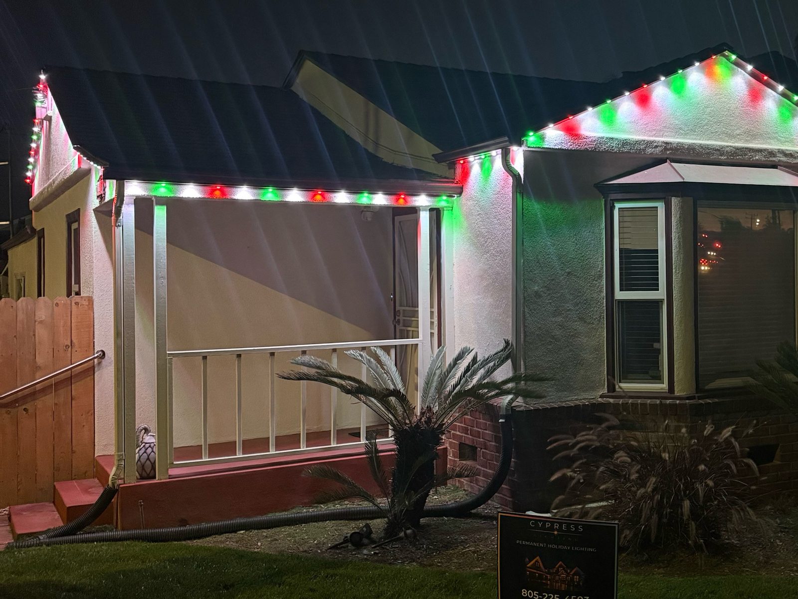 Red, green and white Christmas lighting on a stucco home