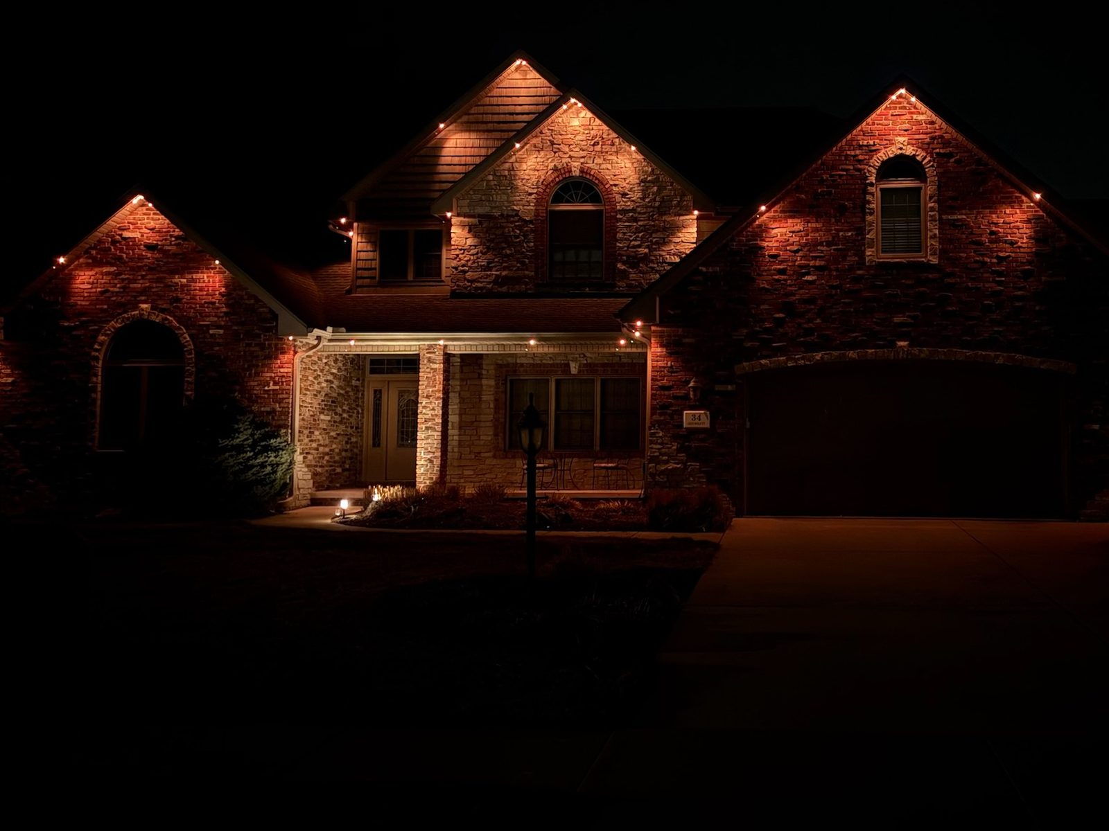 Amber lighting washing a brick and stone home